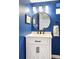 Stylish bathroom featuring a round mirror, vanity with storage, and blue walls at 1557 Fillmore St, Denver, CO 80206