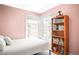 Comfortable bedroom with light pink walls, a large window, and a full bookcase at 1557 Fillmore St, Denver, CO 80206