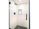 Modern shower with white subway tile, black accents, and pebble floor at 1557 Fillmore St, Denver, CO 80206