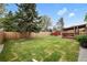 Spacious backyard with a well-maintained lawn, wooden fence, shed, and covered patio at 5329 Flower Cir, Arvada, CO 80002