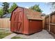 A red wooden storage shed with double doors and a shingled roof at 5329 Flower Cir, Arvada, CO 80002