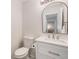 Stylish powder room featuring a modern vanity with a marble countertop and sleek arched mirror at 9855 Chatswood Trl, Highlands Ranch, CO 80126