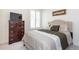 Well-lit bedroom with tufted headboard, dark wood dresser, and bright window at 8761 S Wenatchee Ct, Aurora, CO 80016