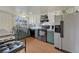 Bright kitchen featuring stainless steel appliances, lower sage-green cabinets, white upper cabinets, and wood-look flooring at 3502 S Kittredge St # C, Aurora, CO 80013