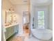 Bright bathroom featuring modern fixtures, a standalone tub, and a view into the bedroom at 541 Fox St, Denver, CO 80204