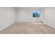 A spacious room with white walls, beige carpet, a door, and a window looking out on greenery at 3102 White Oak Trl, Highlands Ranch, CO 80129