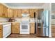 Functional kitchen with stainless steel refrigerator, white appliances, and wood cabinets at 1811 S Yank Ct, Lakewood, CO 80228