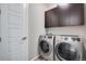 Efficient laundry room equipped with modern washer and dryer units and overhead cabinetry at 3022 Merlin Dr, Brighton, CO 80601