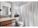 Cozy bathroom featuring a modern vanity, toilet, framed mirror, and decorative striped shower curtain at 15502 E Flower Mound Pl, Parker, CO 80134