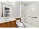 Bright bathroom features a wood vanity, a white tile shower and tub combination, and handicap safety bars at 1526 Braewood Ave, Littleton, CO 80129