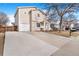 Two-story home with neutral siding, large driveway, attached one car garage, blue sky, and a leafless tree at 1215 Finch Ave, Brighton, CO 80601