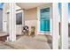 A cozy front porch with a turquoise front door, seating, and neutral colored siding at 1215 Finch Ave, Brighton, CO 80601