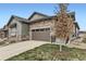 Charming home exterior featuring stone accents, a garage, and a well-kept lawn at 3477 New Haven Cir, Castle Rock, CO 80109