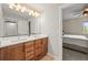 Modern bathroom with double vanity, wood cabinets, large mirrors, and an open doorway to the bedroom at 16312 Morning Rise Ln, Monument, CO 80132