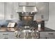 A close up view of the stainless-steel gas range, hood, granite countertops, and gray cabinets at 16312 Morning Rise Ln, Monument, CO 80132