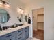 Modern bathroom showcasing a double vanity with marble countertop and a walk-in closet at 7746 S Valdai Ct, Aurora, CO 80016