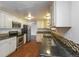 Well-lit kitchen featuring stainless steel appliances, black counters, and warm wood floors at 17209 E Evans Dr, Aurora, CO 80013