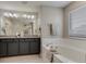 Bright bathroom with soaking tub, granite counters, and gray cabinets at 16544 E 118Th Dr, Commerce City, CO 80022