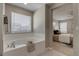 Bright bathroom with a soaking tub and view into an adjacent bedroom at 16544 E 118Th Dr, Commerce City, CO 80022