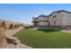 Spacious backyard featuring artificial turf, a stone retaining wall, and a covered patio for outdoor entertaining at 9443 Torrey Way, Arvada, CO 80007