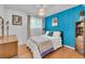 Bright bedroom with a blue accent wall, wood floors, and natural light at 1648 S Locust St, Denver, CO 80224