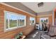 Relaxing sunroom featuring wood-paneled walls, three windows with peaceful backyard views, and exercise equipment at 68251 E 96Th Ave, Byers, CO 80103