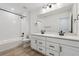 Modern bathroom featuring dual sinks, white cabinets, and shower with white tile at 9243 Truckee Ct, Commerce City, CO 80022