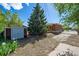 A backyard with a shed and a mature tree that provides shade, offering outdoor space for relaxation and activities at 392 Central Ave, Brighton, CO 80601