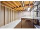 Unfinished basement with exposed wood beam ceiling, concrete floor, and workbench ready to be customized at 392 Central Ave, Brighton, CO 80601