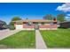 Inviting single-story home with a brick facade, manicured lawn, and convenient driveway access at 392 Central Ave, Brighton, CO 80601