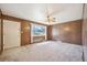 Empty living room with wood paneling, neutral carpet, and a bright window at 392 Central Ave, Brighton, CO 80601