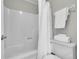 This is a bathtub and toilet with a shower curtain, white walls, and rolled towels at 2971 S Sheridan Blvd, Denver, CO 80227