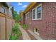 Exterior side view showcasing brick facade, walkway, lush landscaping, and privacy fence at 836 Steele St, Denver, CO 80206
