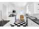 Galley kitchen featuring granite counters, subway tile backsplash, stainless appliances and black and white checkered floors at 2655 S Humboldt St, Denver, CO 80210