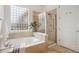 Bathroom featuring a large tub, a glass-enclosed shower, travertine-style tile and decorative plant at 2100 N Humboldt St # 302, Denver, CO 80205