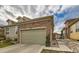 Home featuring a two-car garage with a stone facade and well-maintained landscaping at 12715 Madison St, Thornton, CO 80241