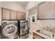 Laundry room featuring washer and dryer, storage cabinets, and a utility sink at 12715 Madison St, Thornton, CO 80241