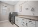 Modern laundry room with gray washer and dryer, white cabinets, and stylish decor at 6733 S Waterloo Ct, Aurora, CO 80016