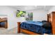 Comfortable bedroom with a wood frame bed, plush blue blanket, and window view at 3546 S Depew St # 103, Denver, CO 80235