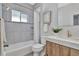 Bright bathroom featuring tub with tile surround, floating vanity, and brushed gold fixtures at 4036 Navajo St, Denver, CO 80211