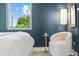 Bright bedroom with a cozy white chair, modern lighting, and a serene outdoor view from the window at 2107 S Grant St, Denver, CO 80210