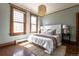 Light-filled bedroom with hardwood floors, a large bed, and two windows with beautiful wood trim at 1620 Dahlia St, Denver, CO 80220