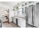 Stylish white kitchen boasts stainless steel refrigerator, wine cooler and hanging plants at 1620 Dahlia St, Denver, CO 80220