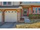 Close up view of home's brick facade, front entrance and two-car garage at 13294 W 65Th Dr, Arvada, CO 80004