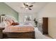 The bedroom features a plush bed, accent wall, ceiling fan, and bright window overlooking neighborhood trees at 803 E 98Th Ave # 105, Thornton, CO 80229