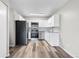 Well-lit kitchen featuring stainless appliances, white cabinetry, stone countertops, and wood-look floors at 795 S Alton Way # 11C, Denver, CO 80247