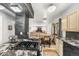 Open concept kitchen with cooktop island, black stone pillar, eat-in table and access to living room at 3191 S Holly Pl, Denver, CO 80222