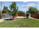 Spacious backyard featuring green grass, a large tree, two storage sheds, a concrete patio, and wood fencing at 1455 W Alaska Pl, Denver, CO 80223