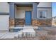 Inviting covered porch with stone accents, a blue front door, and classic railing detail at 12815 Randles Ave, Parker, CO 80134
