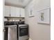 Efficient laundry room featuring modern front-load washer and dryer set with white cabinets and tasteful decor at 12815 Randles Ave, Parker, CO 80134